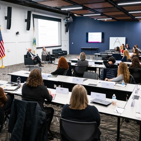 A conference featuring people seated at rows of tables.