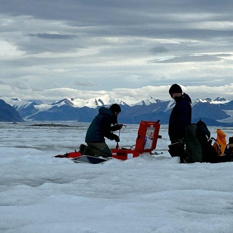 Two people setting up equipment on a vast ice field