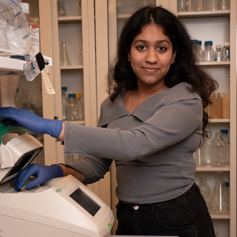 A woman wearing latex gloves and standing next to a piece of equipment.