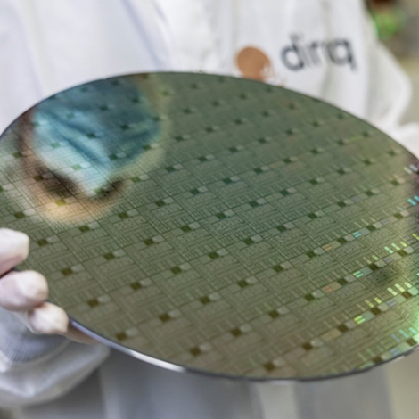 Gloved hands holding a foot-wide round computer wafer